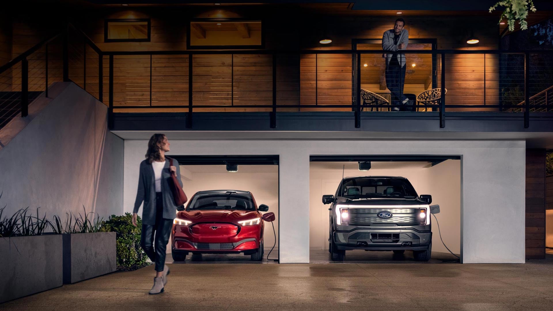 Woman walking out from home garage with a 2024 Mustang® Mach-E and Ford Lightning® truck in plugged-in and charging | Champion Ford in Owensboro KY